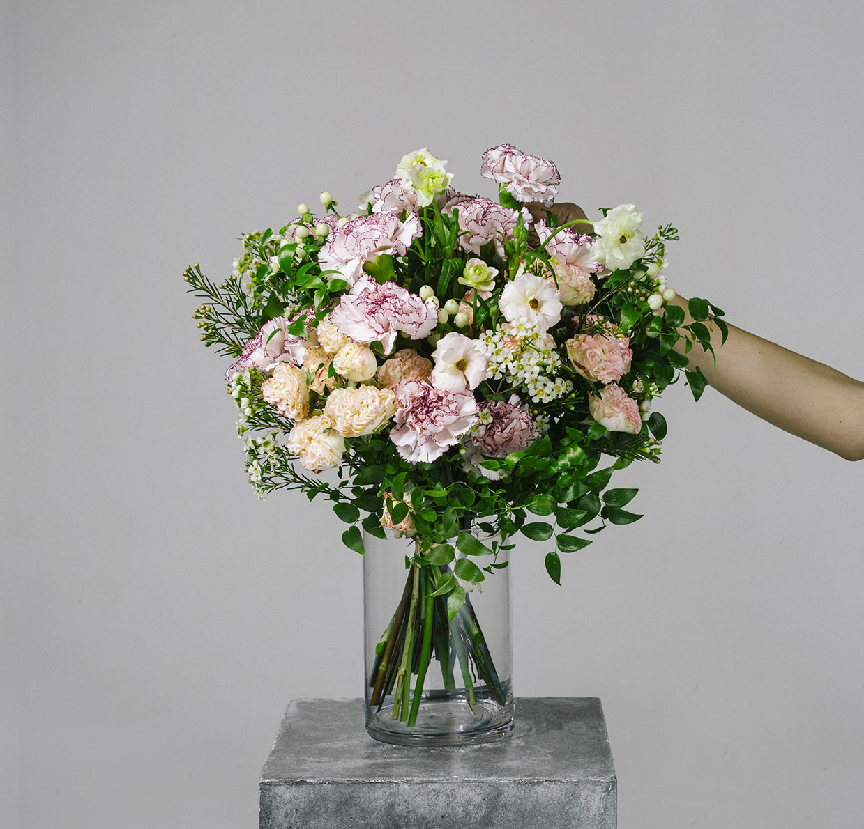 florist arranging a flower bouquet of pink carnation and ranunculus for the bespoke collection