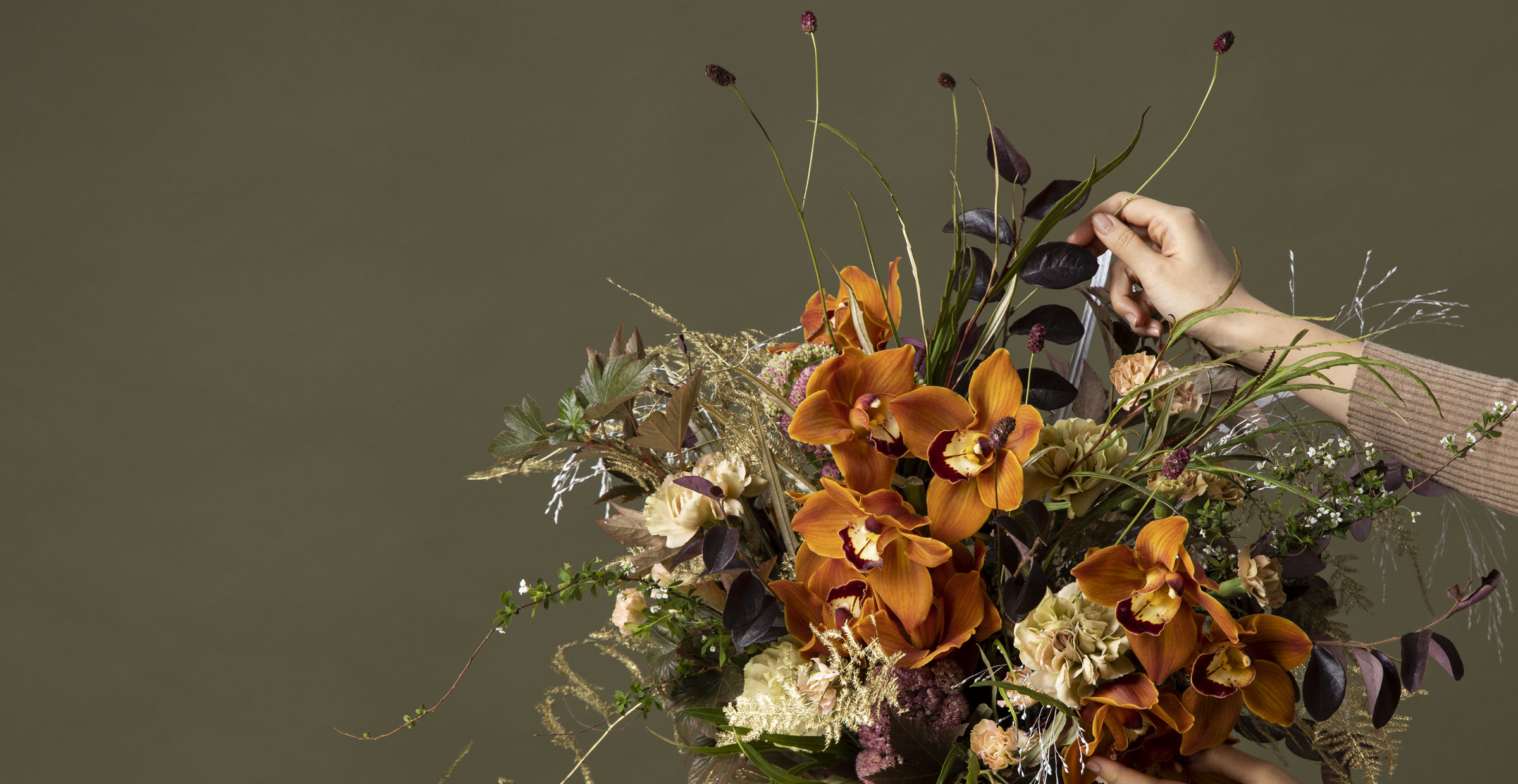 Banner image of a florist arranging a flower bouquet of golden orchids for the online flower collection